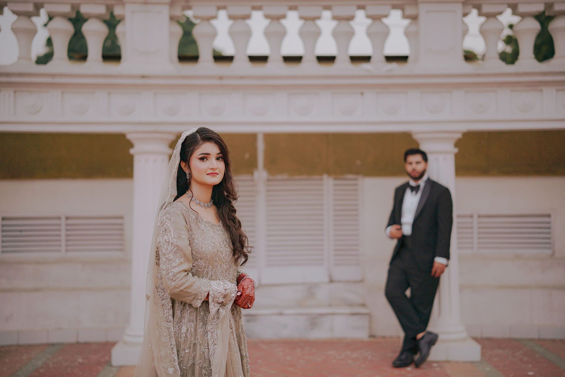 Bride and groom walking past a white colonnade, editorial Lahore wedding photography