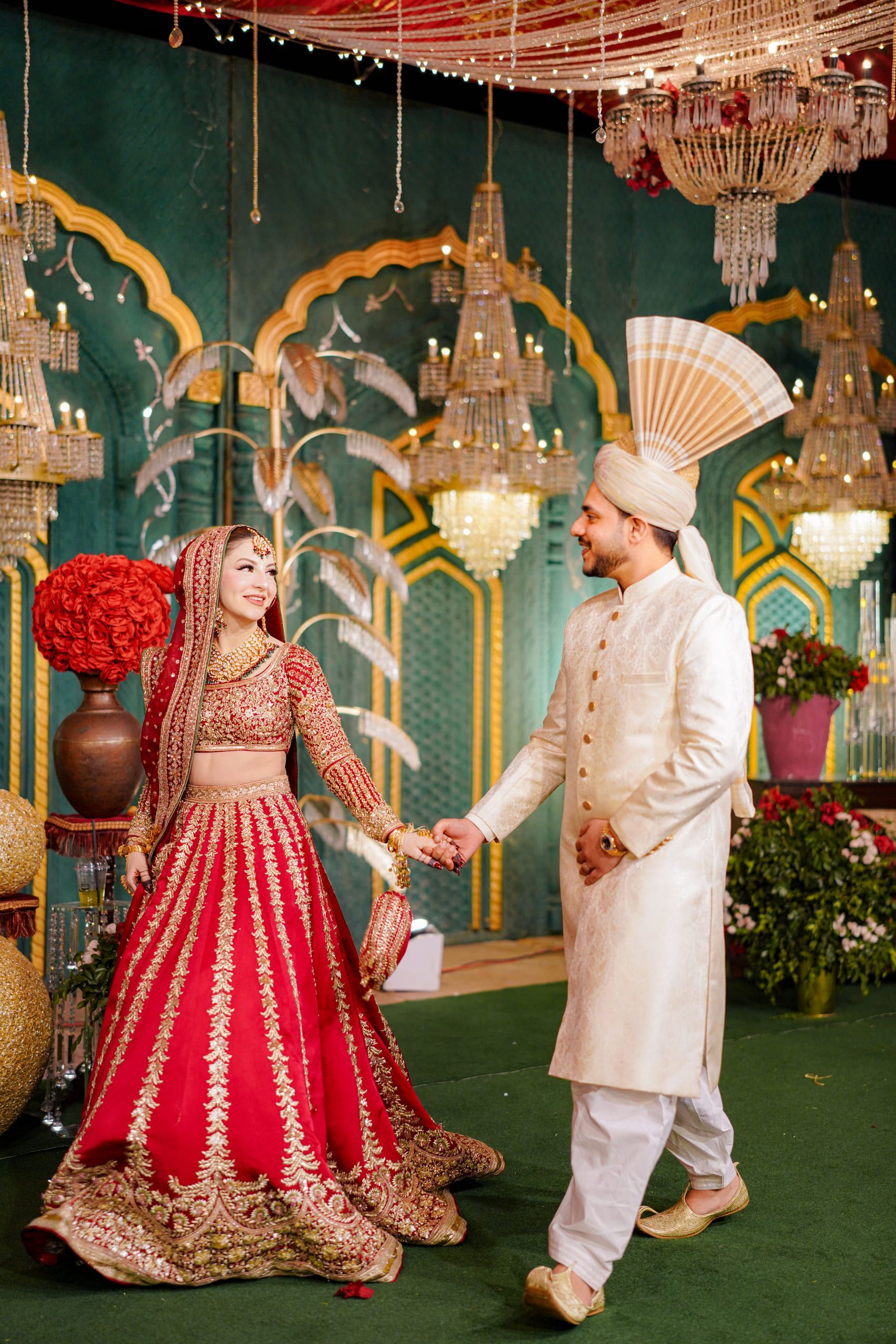 Couple holding hands on a decorated reception stage, Lahore wedding photography